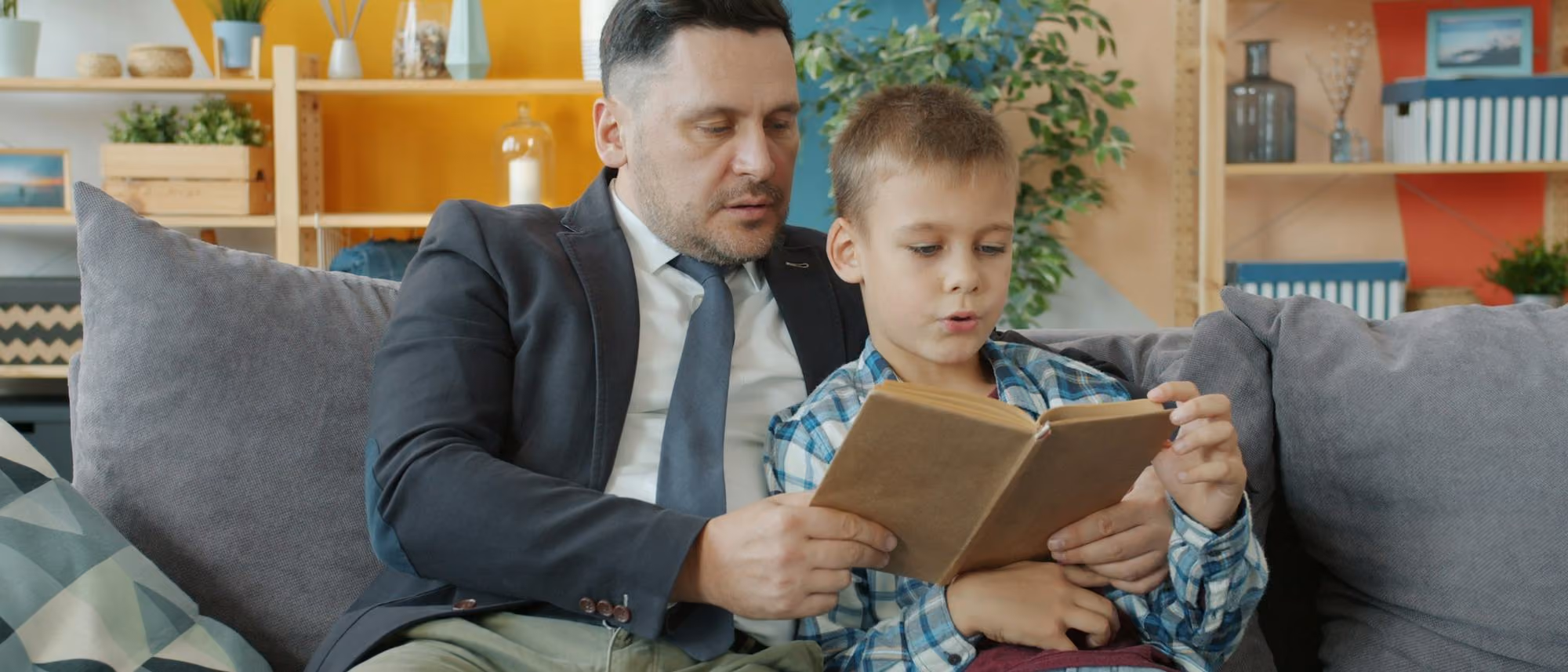 Pai e filho sentados no sofá olhando juntos para um tablet