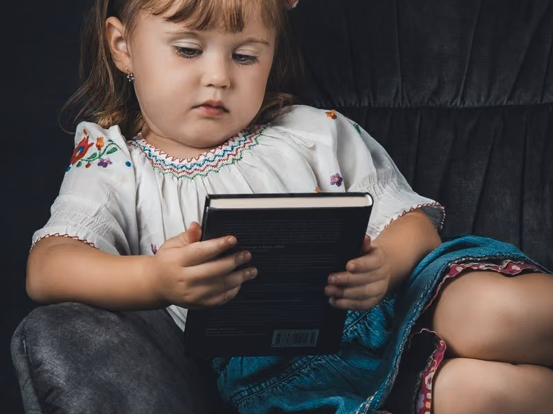 Criança lendo um livro sentada no chão da sala